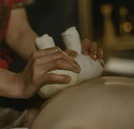 Hands massage wrapped ankles on a person’s leg in a spa setting.