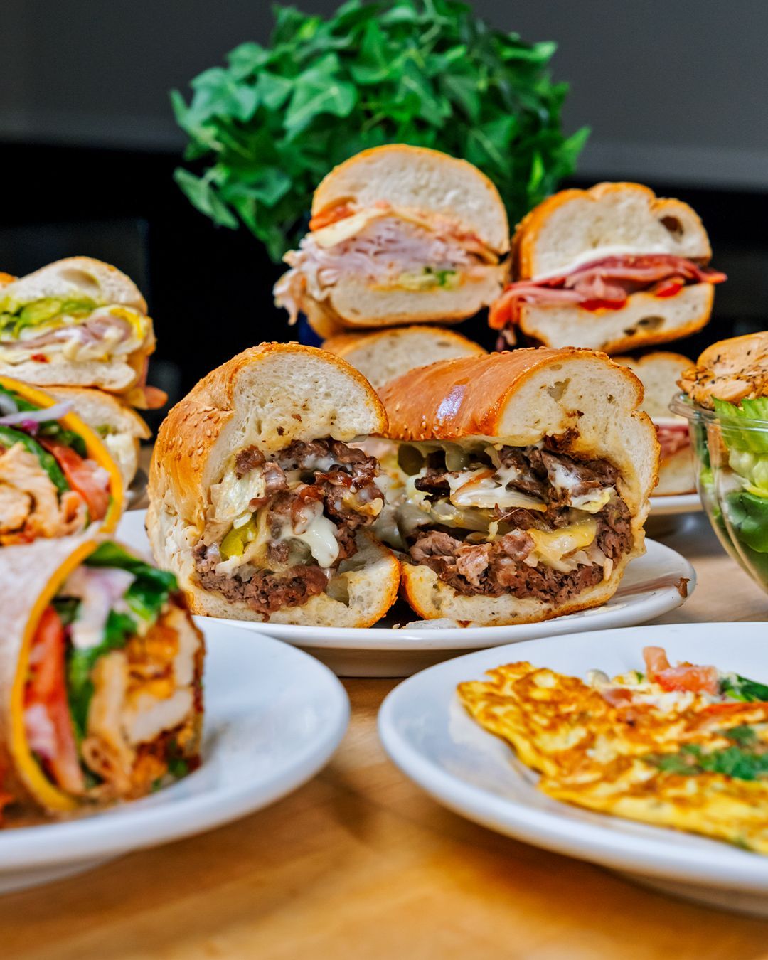 A variety of sandwiches and wraps are on plates on a table.