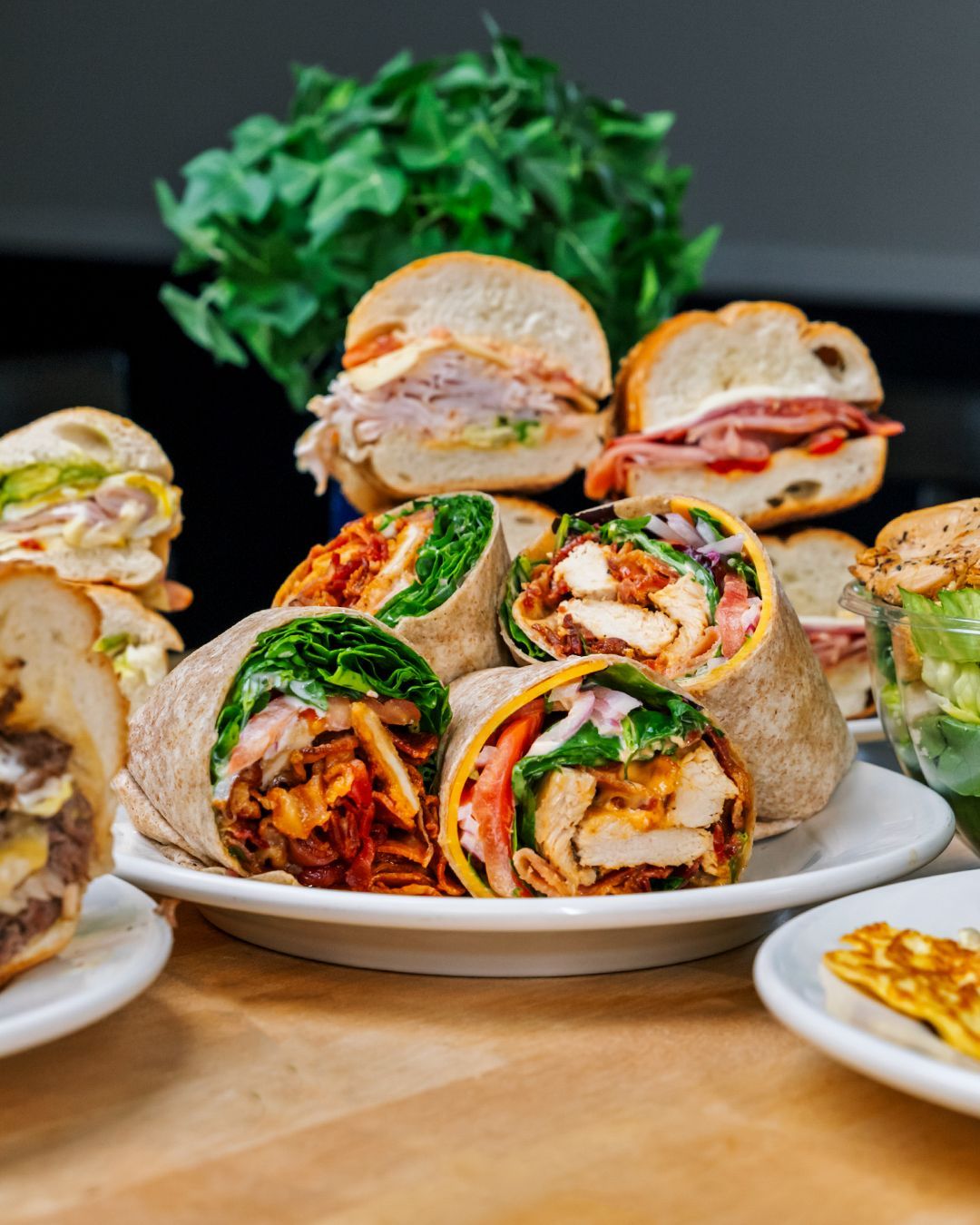 A plate of sandwiches and wraps on a wooden table.