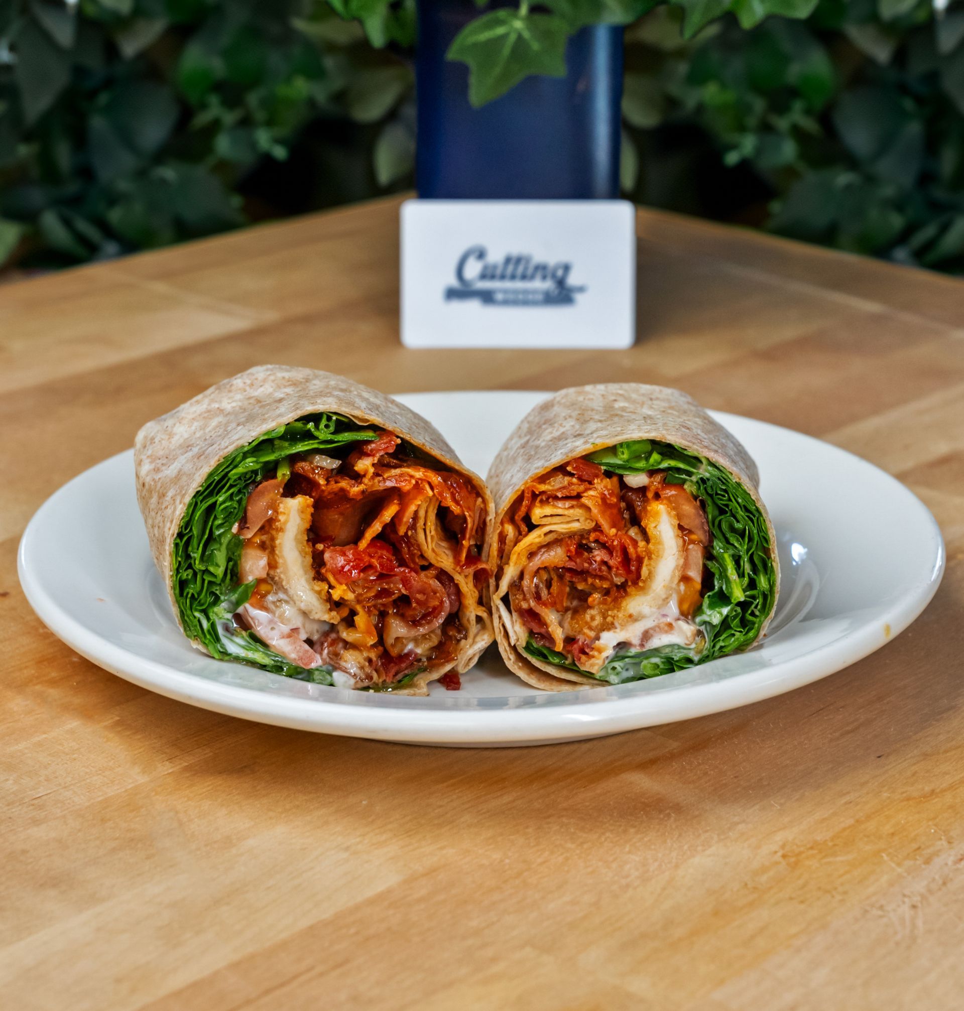 Two wraps are on a white plate on a wooden table.