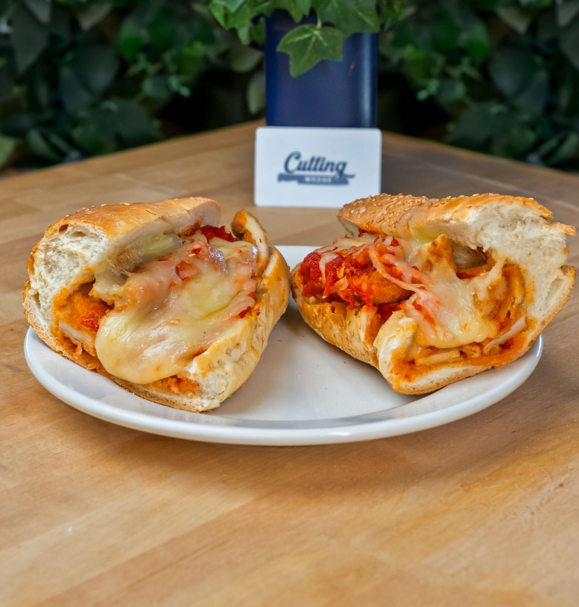 Two sandwiches are cut in half on a white plate on a wooden table.