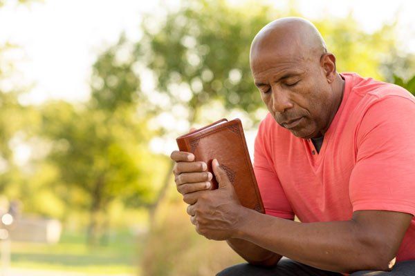 man praying with book in hand