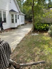 Newly poured concrete driveway next to a white house. A worker is visible.