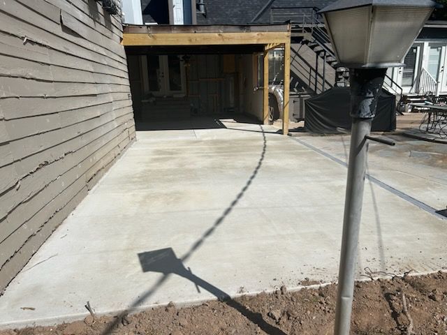 A concrete patio next to a building with a covered walkway and lamppost.