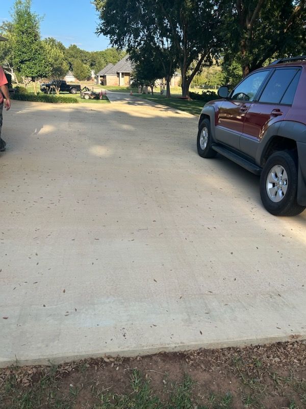 Red SUV parked on a concrete driveway. A person stands on the left. Houses and trees in the background.