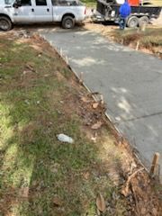 Concrete driveway under construction with truck and person. Grassy area to the side.