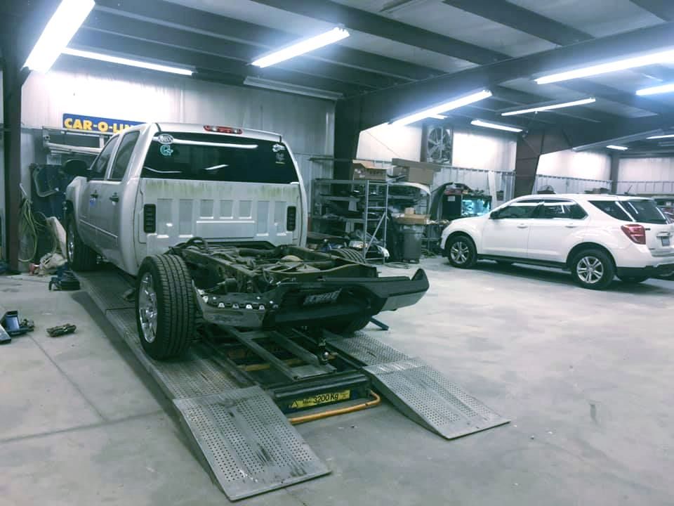A truck is sitting on a lift in a garage.
