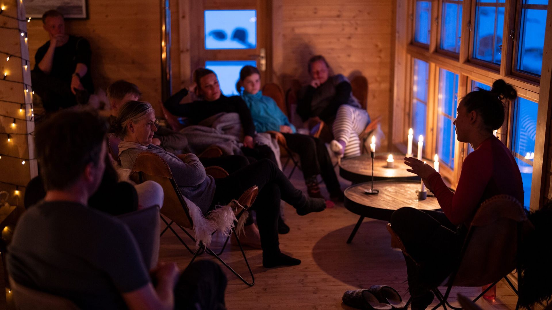 Folk samledes i en hytte oplyst af stearinlys og lyskæder og lyttede til en kvinde, der talte.