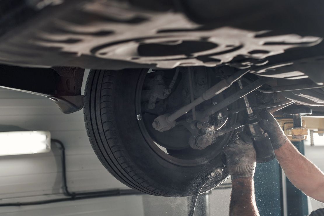 Meccanico mentre ispeziona la ruota e il sottoscocca di un’auto in un’officina