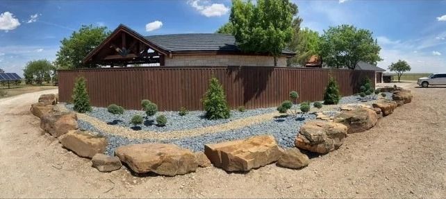 Rustic brown building with stone landscaping and desert rocks under a blue sky