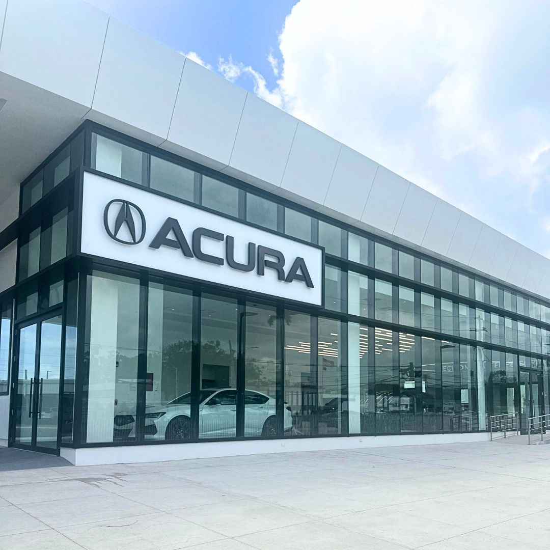 Acura dealership with large glass windows; white exterior, car visible inside.
