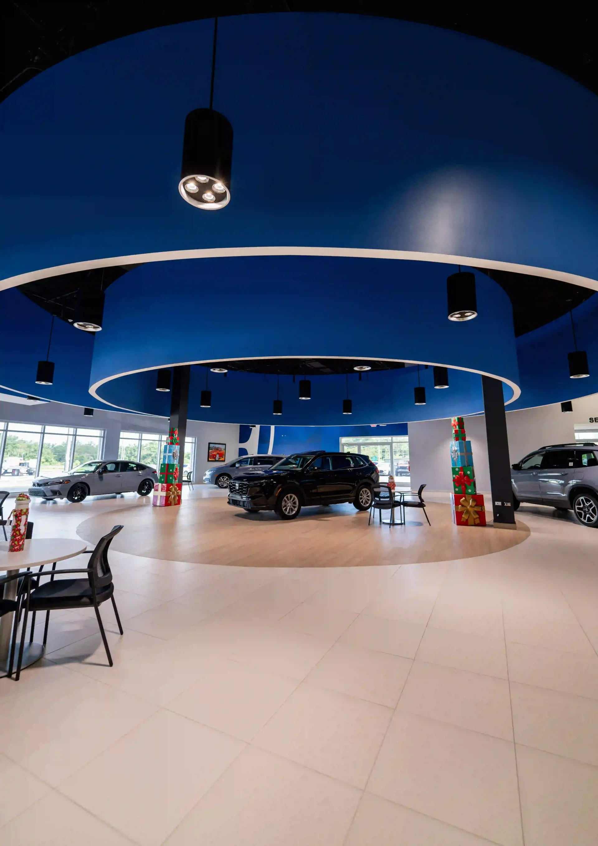 Modern car showroom with blue ceiling, tiled floor, and vehicles on display