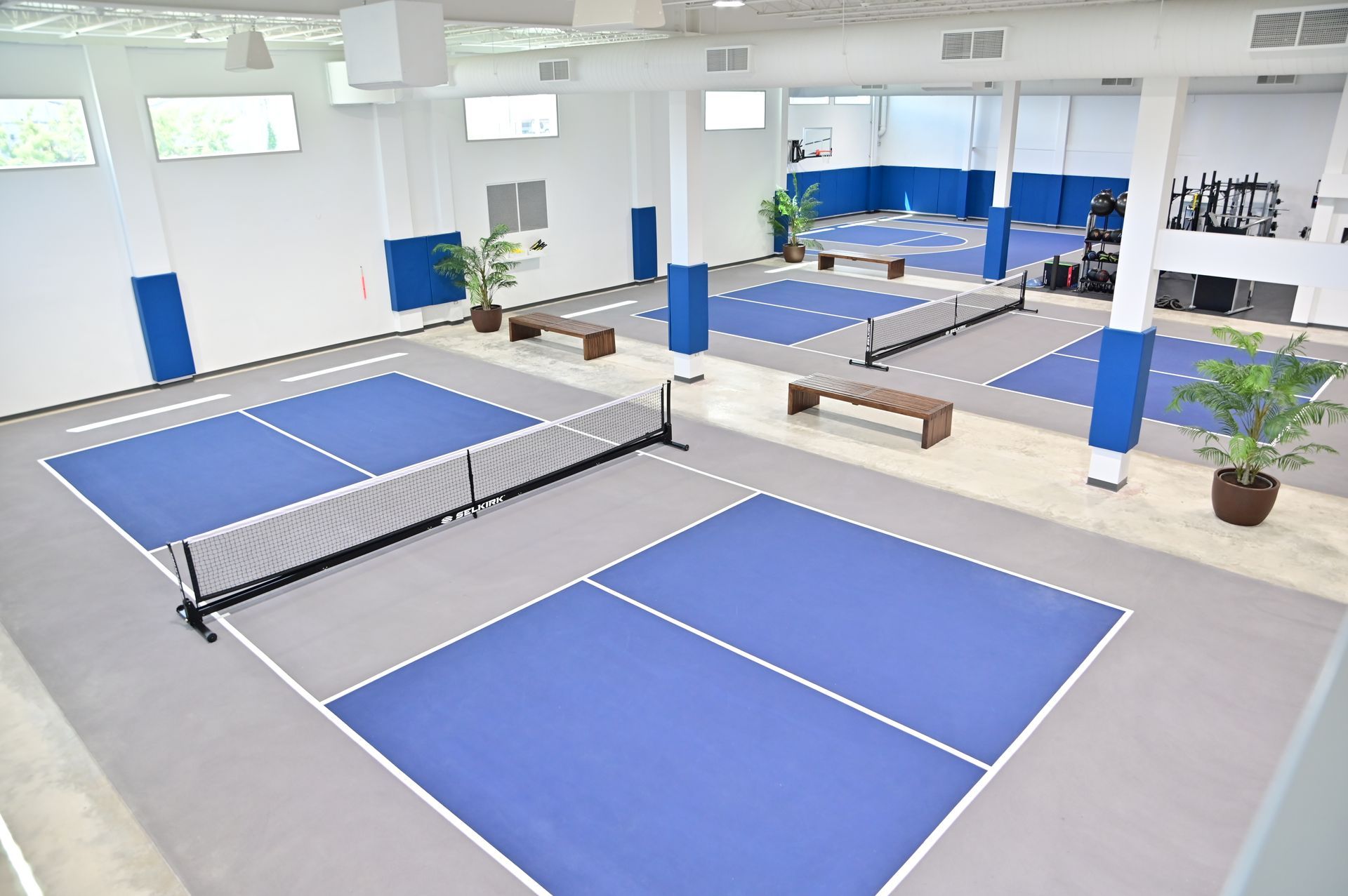 A large indoor picket ball court with blue and white courts built by DEV Builders