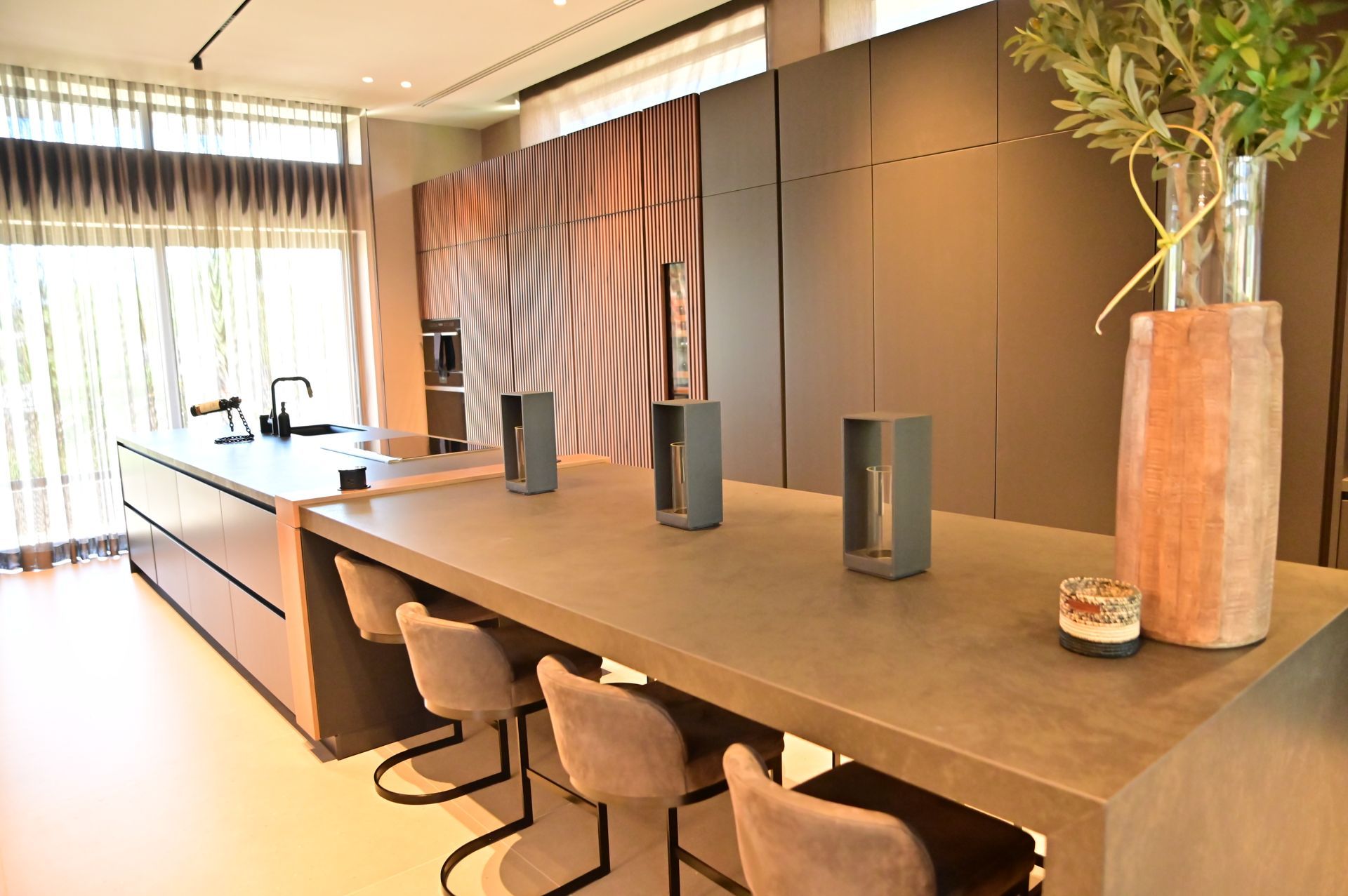 A kitchen with a long table and chairs and a vase of flowers on it designed by DEV Builders