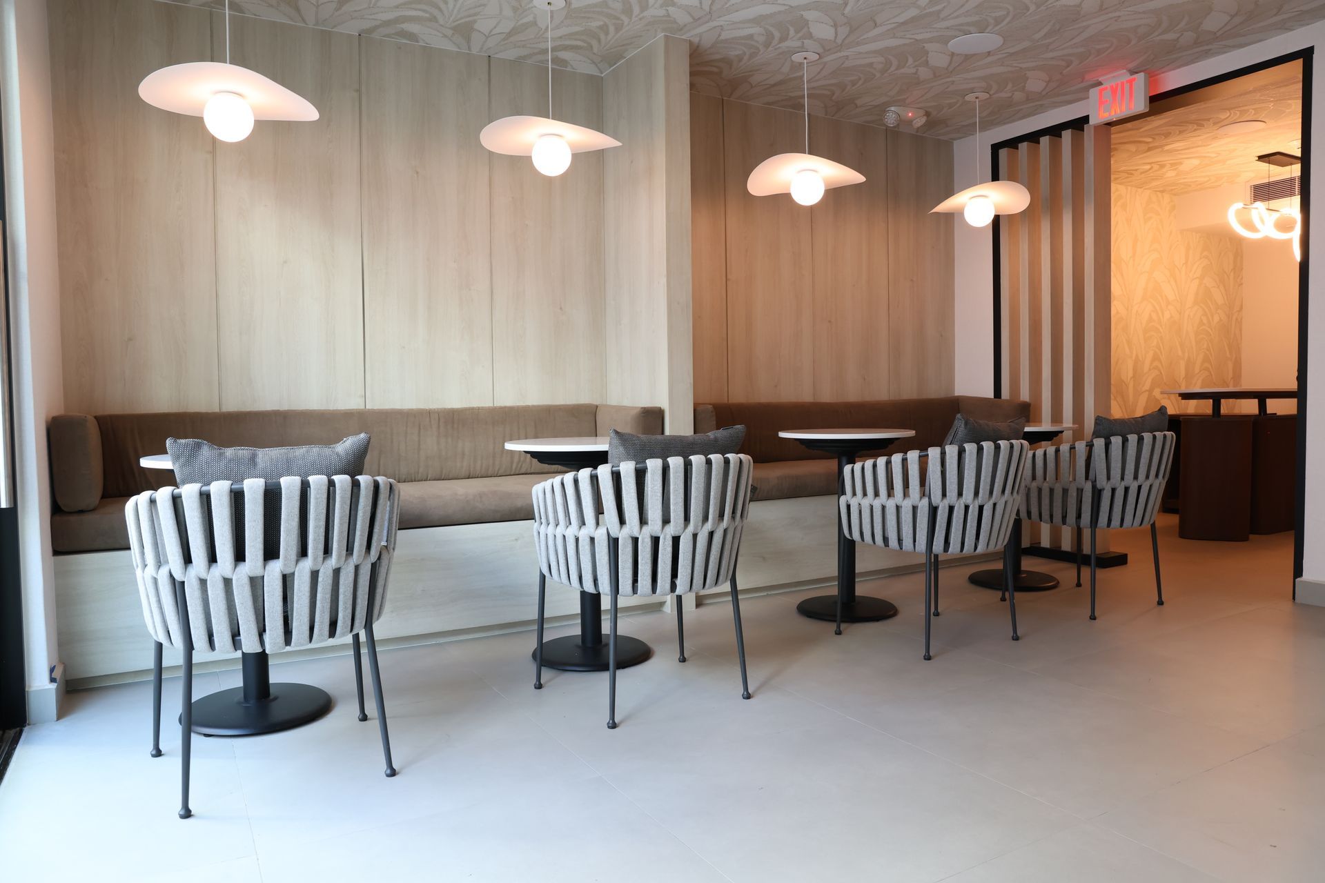 Sunlit restaurant dining tables set with wine glasses and cutlery near large windows