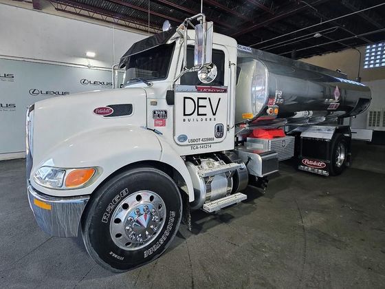 A white truck with the word dev on the side is parked in a garage.