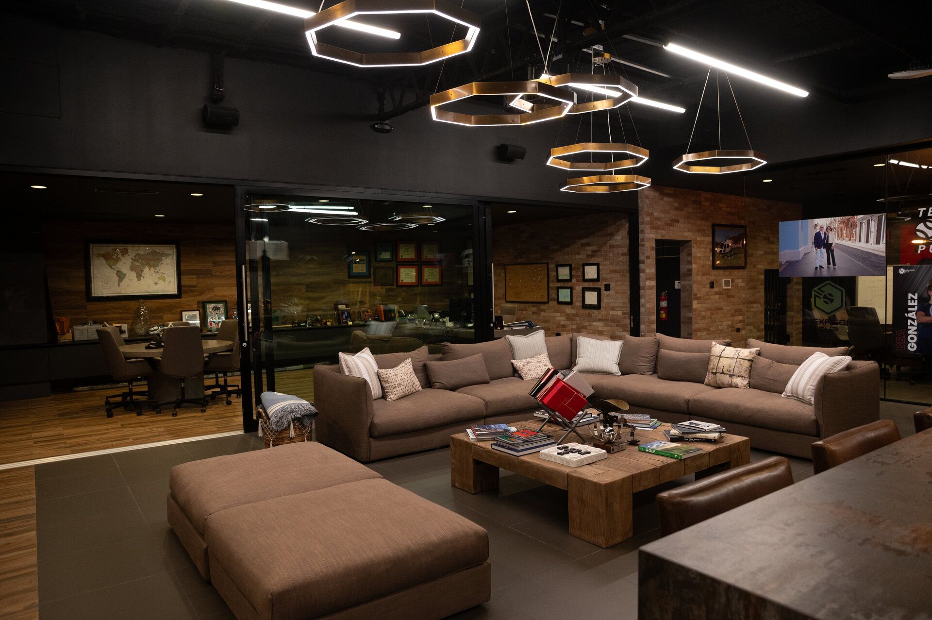 Modern living room with brown sectional, ottoman, wood coffee table, and unique lighting.