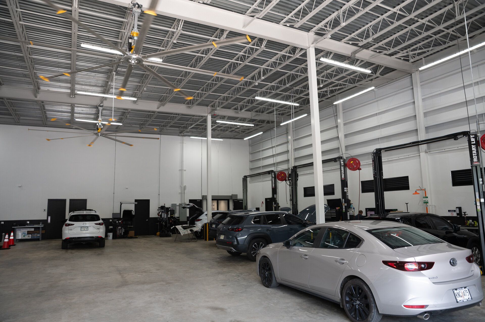 Interior of an auto repair shop with several vehicles on lifts and parked on the floor.