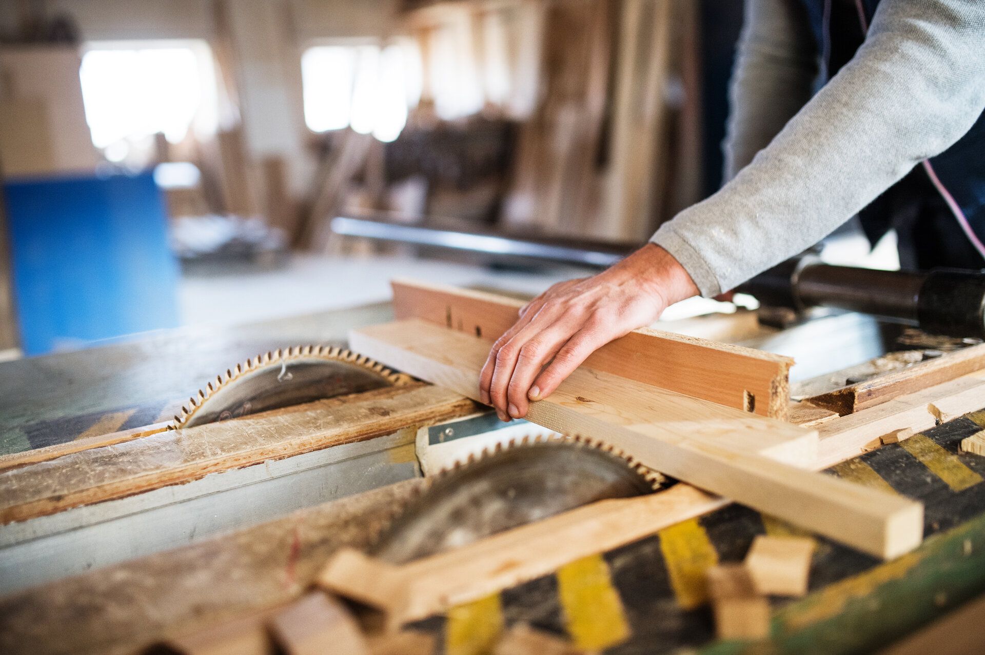 Person using a table saw to cut wood in a workshop.
