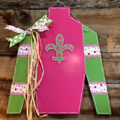 Pink and green decorative paper apron with fleur-de-lis, tied with ribbons on a rustic wooden surface