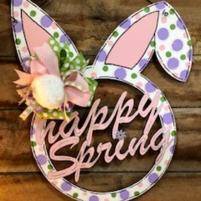 Spring wreath with bunny ears and pastel “happy spring” lettering on a wooden background
