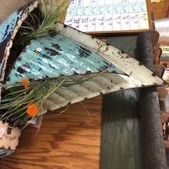 Decorative fish sculpture with blue, white, and black feathers on a wooden table