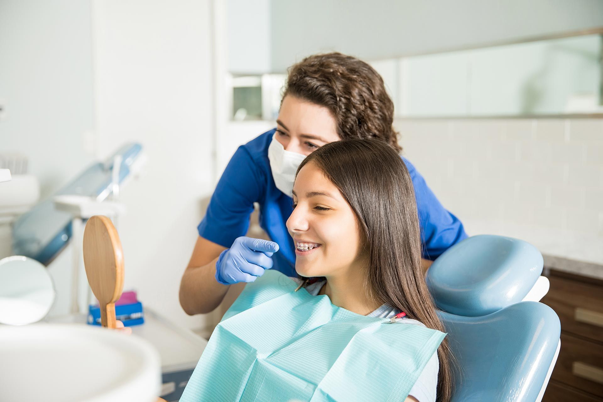 Teen girl smiling with new braces at orthodontist appointment with dental hygienist. Teen girl smiling with new braces at orthodontist appointment with dental hygienist.
