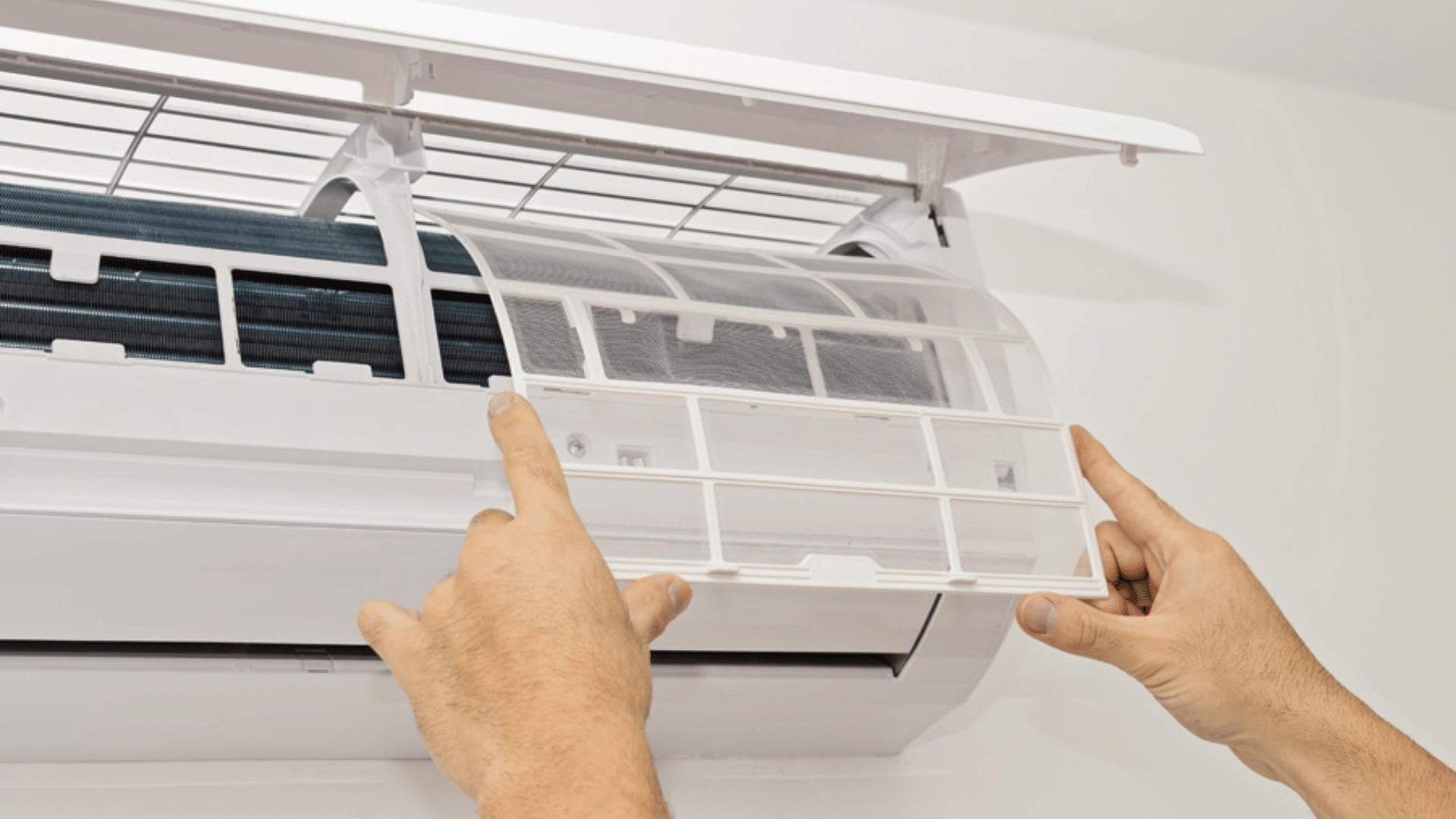 A person is cleaning the filter of an air conditioner.