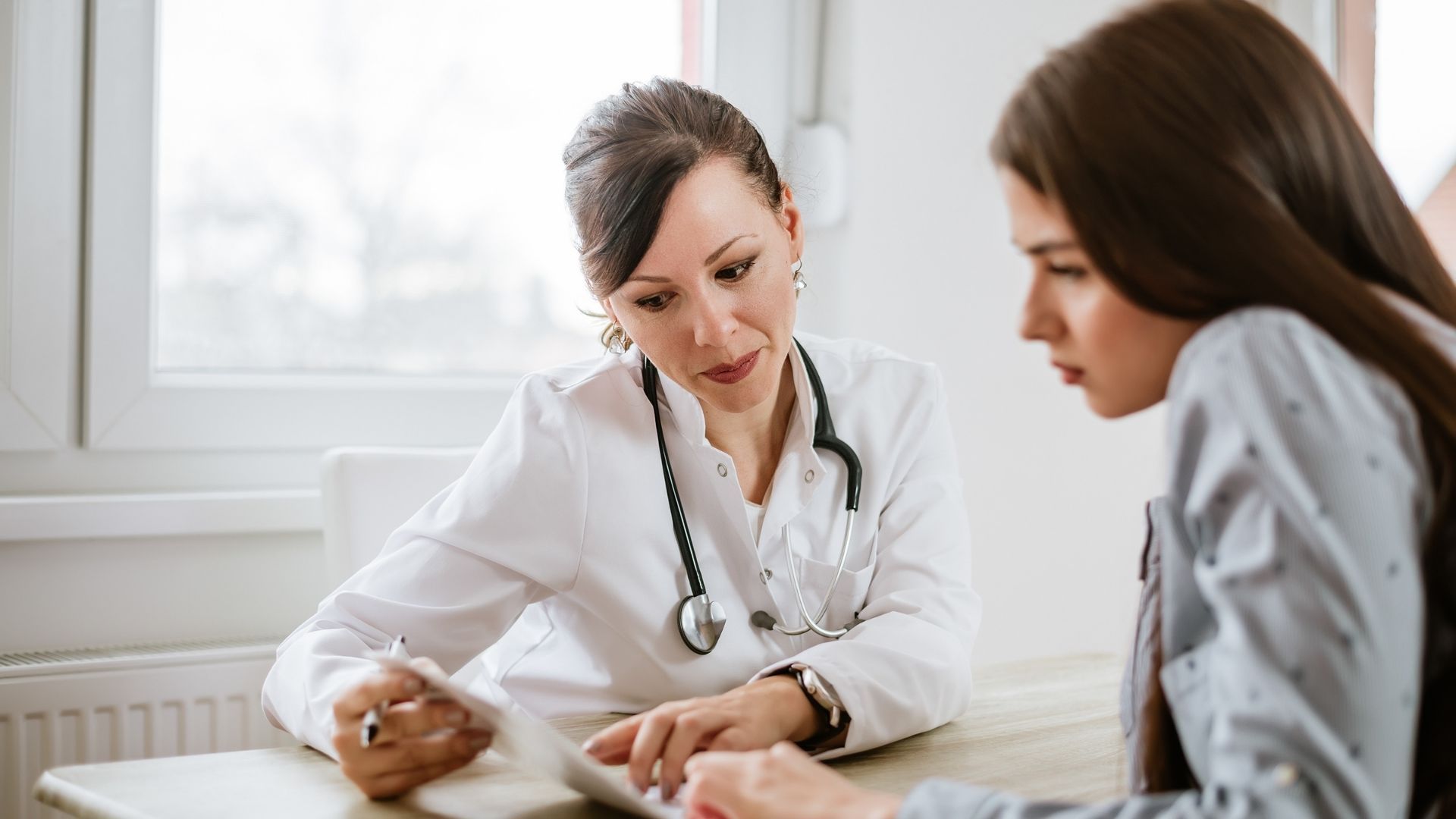 A doctor is talking to a patient who is sitting at a table.