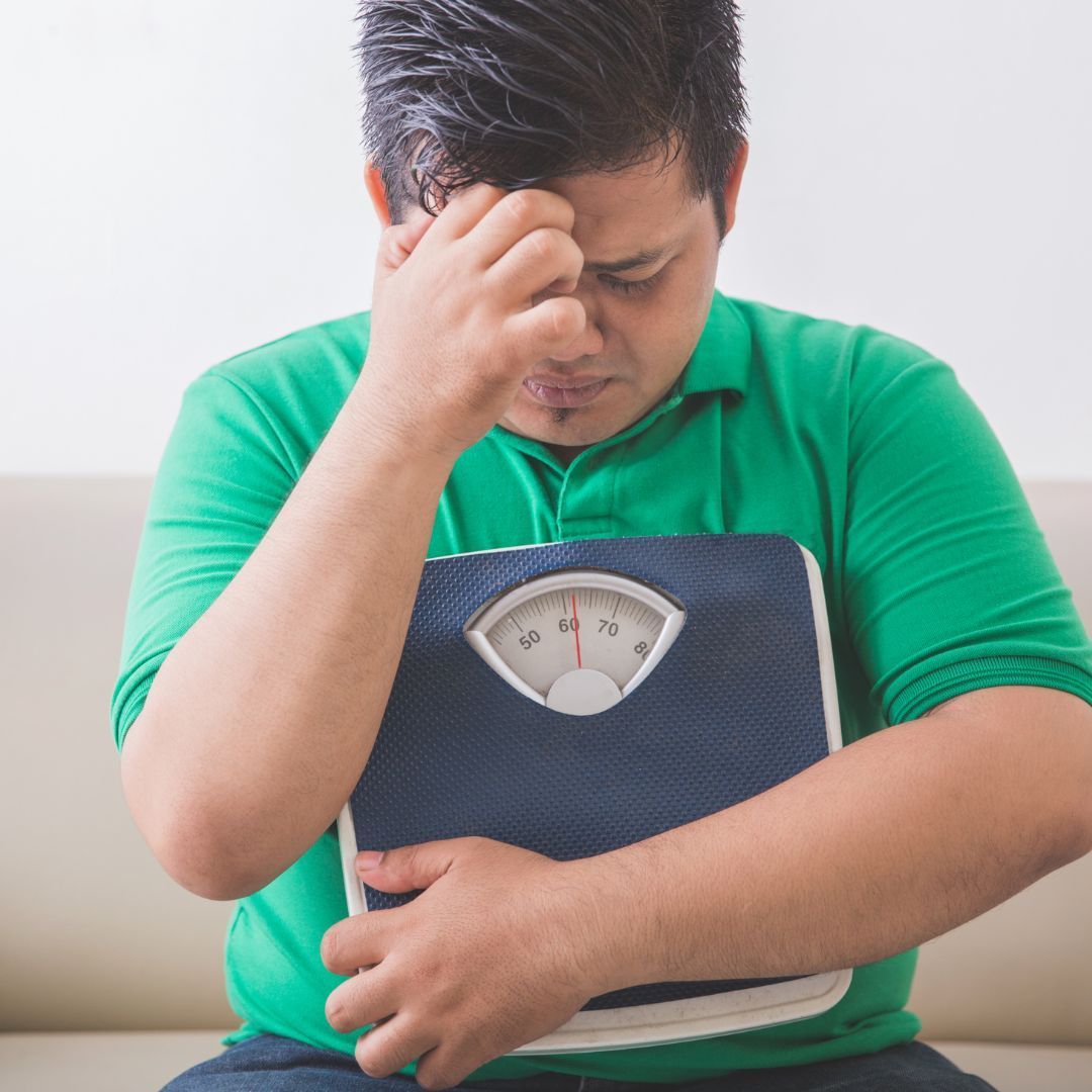 A man in a green shirt is holding a scale in his hands