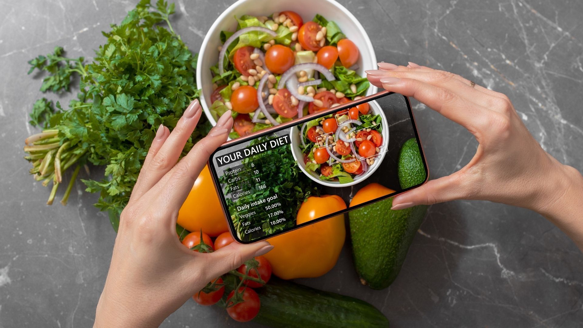 A person is taking a picture of a salad with a cell phone.