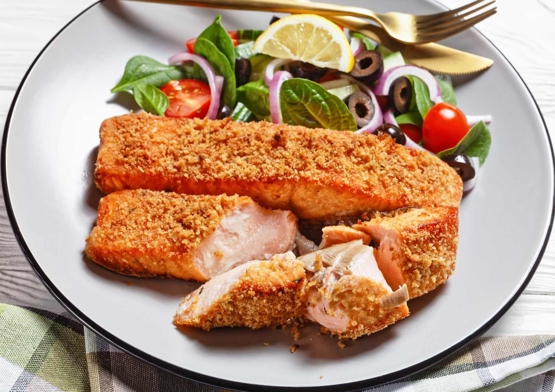 A white plate topped with breaded salmon and a salad.