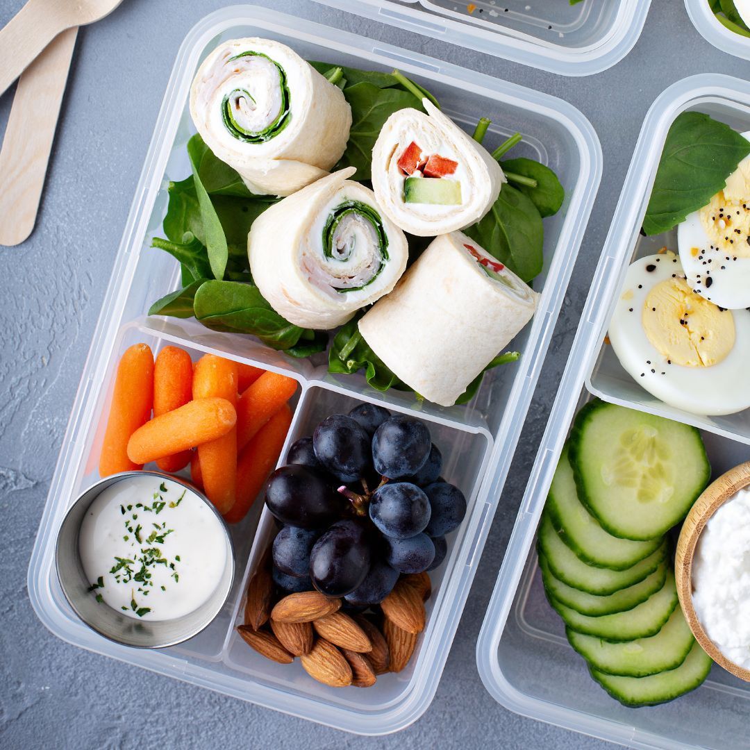 a row of lunch boxes filled with different types of food on a purple background .
