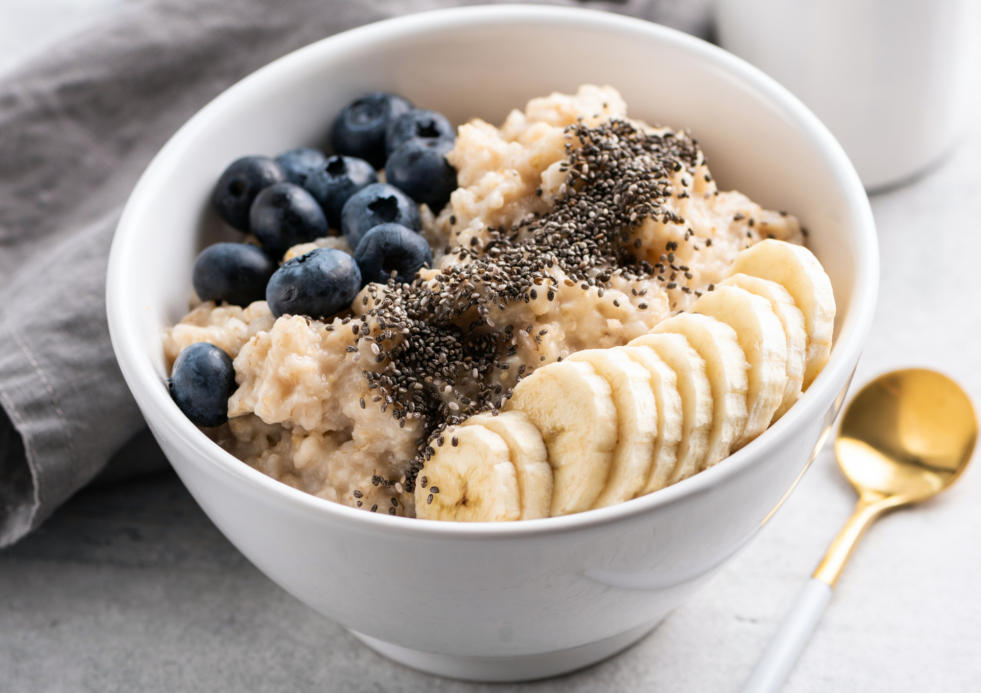 A bowl of oatmeal with bananas , blueberries and chia seeds.