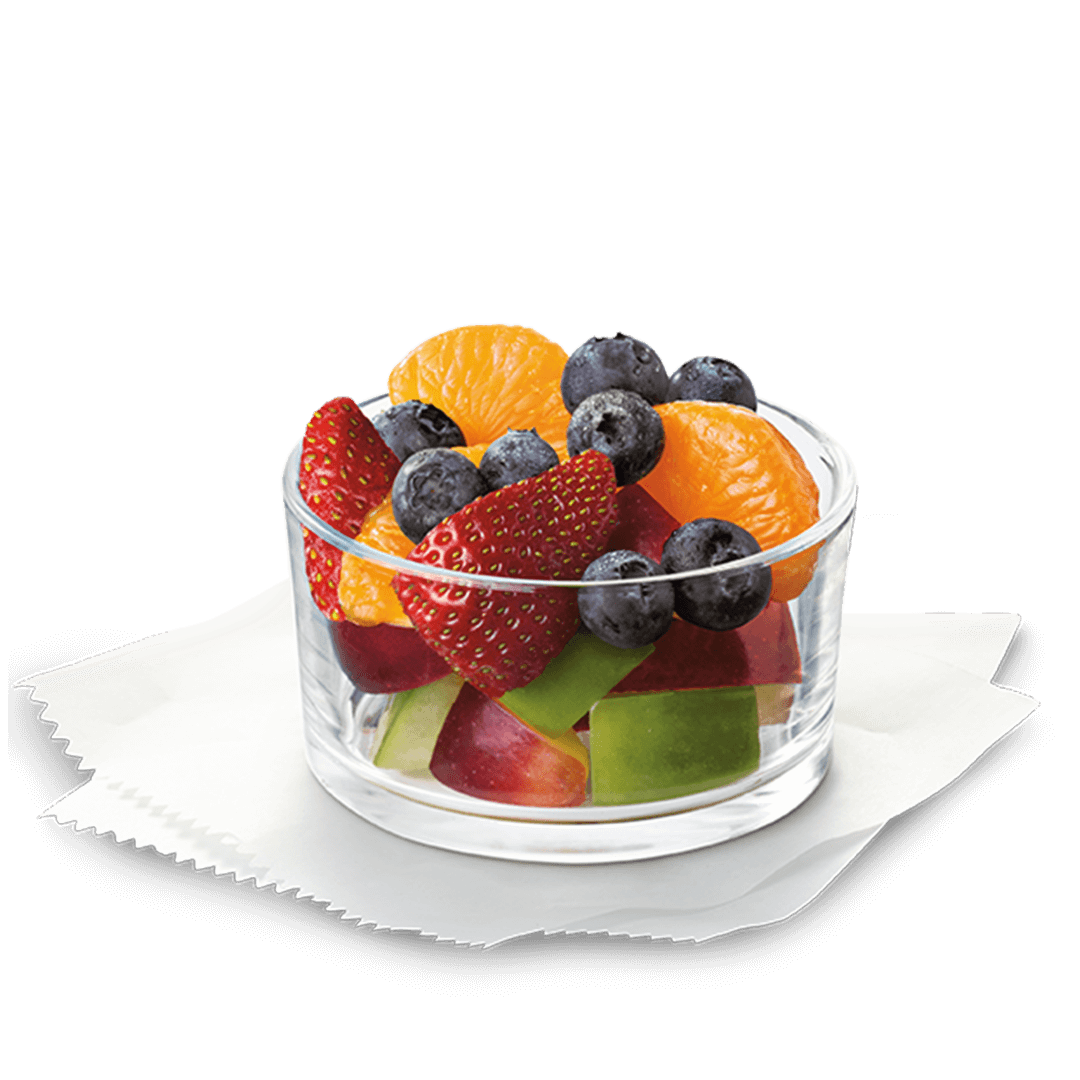 A glass bowl filled with strawberries , blueberries , oranges and apples.