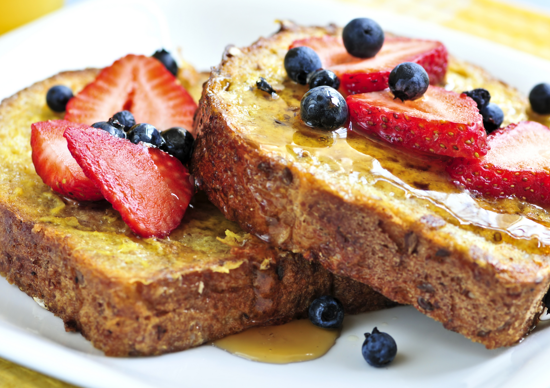 French toast with strawberries and blueberries on a white plate