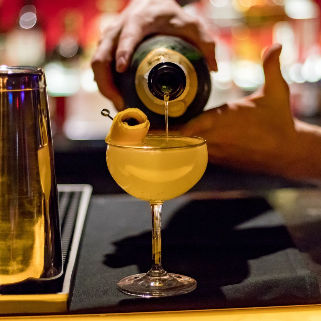 A bartender pours a drink into a martini glass