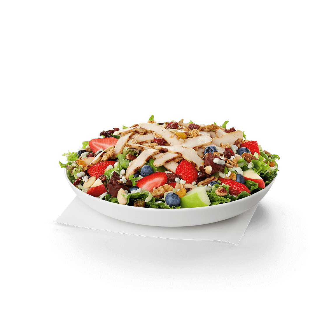 A salad with strawberries , blueberries , apples and chicken on a white plate. Chick fil A Macros