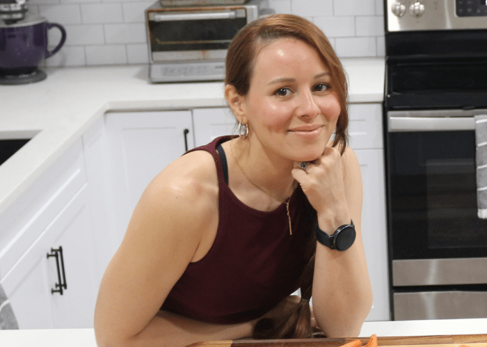 A woman in a kitchen with her hand on her chin