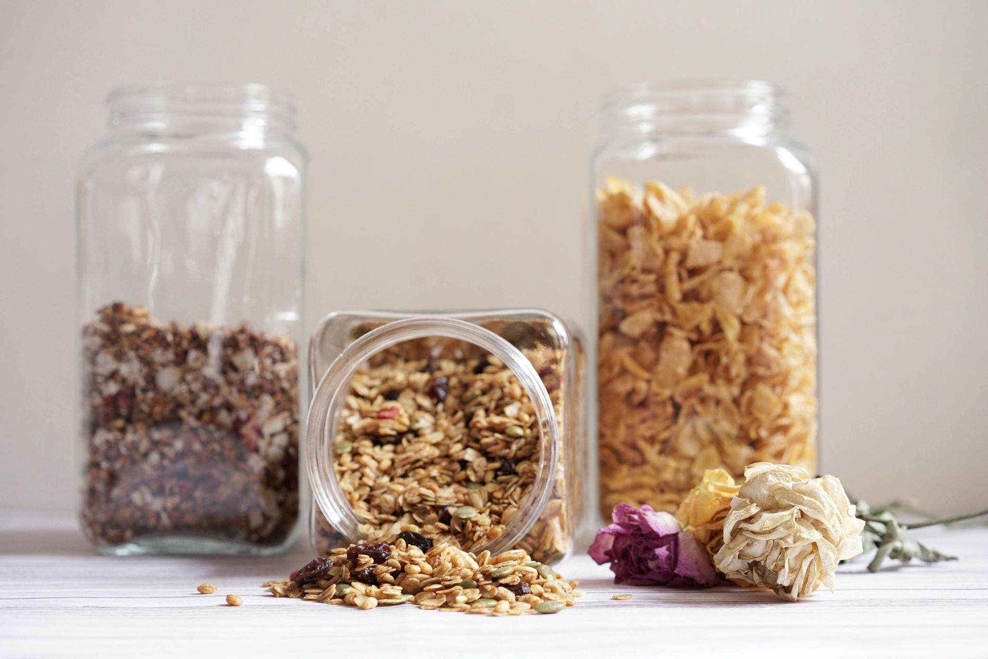 Three glass jars filled with different types of food are sitting on a table.