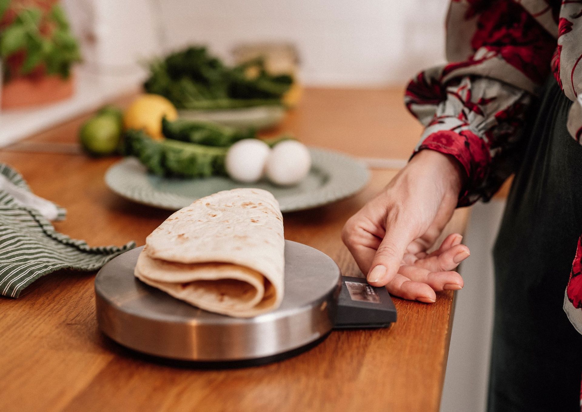 A woman is weighing a tortilla on a scale.