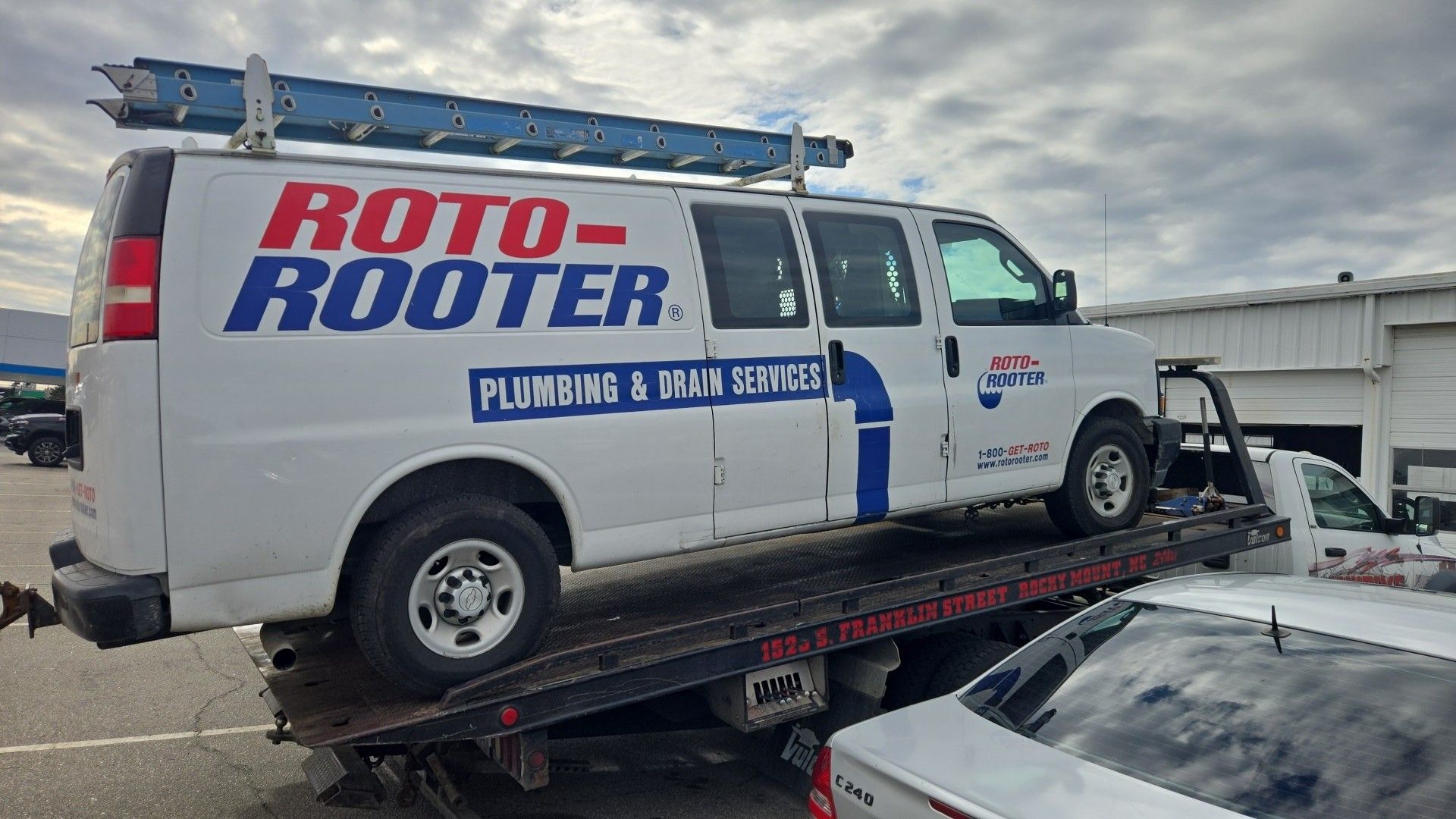 White Roto-Rooter plumbing van on a tow truck, ladder on top in Rocky Mount, NC.