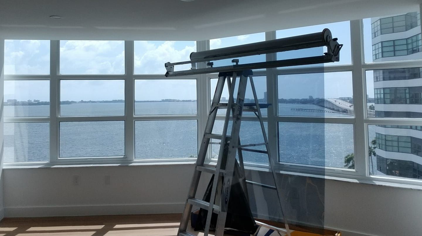 Ladder by window with a view of water and buildings.