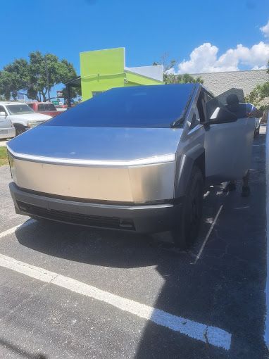 Tesla Cybertruck parked, door open, on a sunny day.