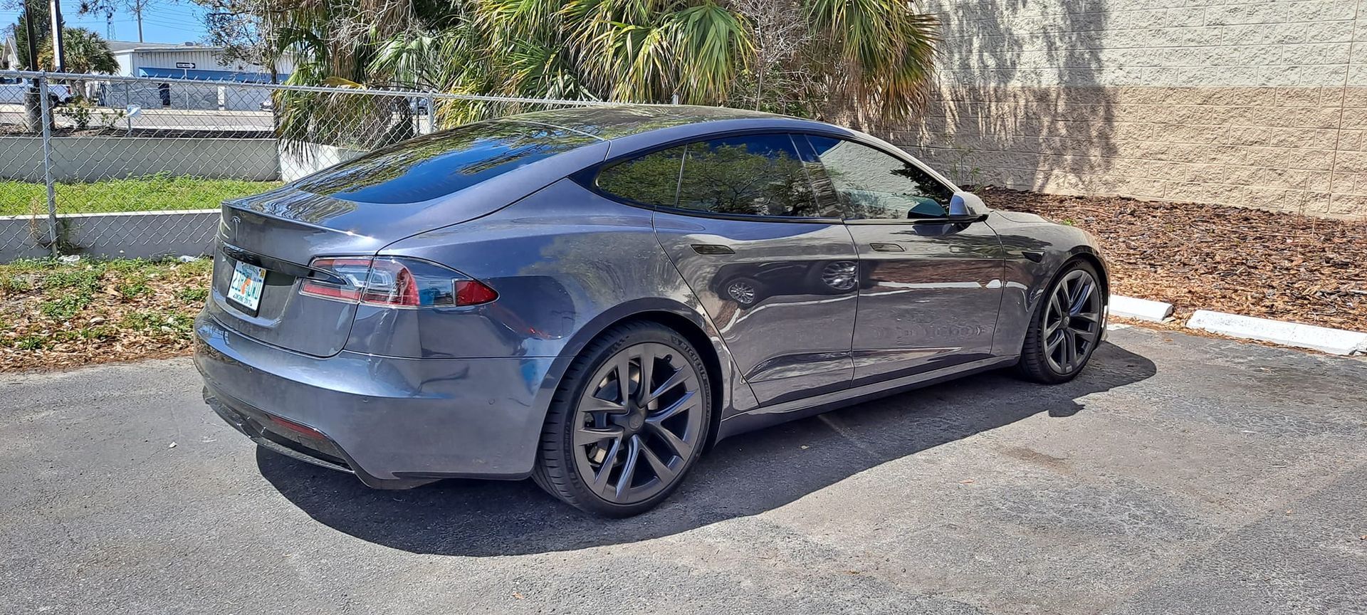 A gray Tesla sedan parked in a parking lot on a sunny day.