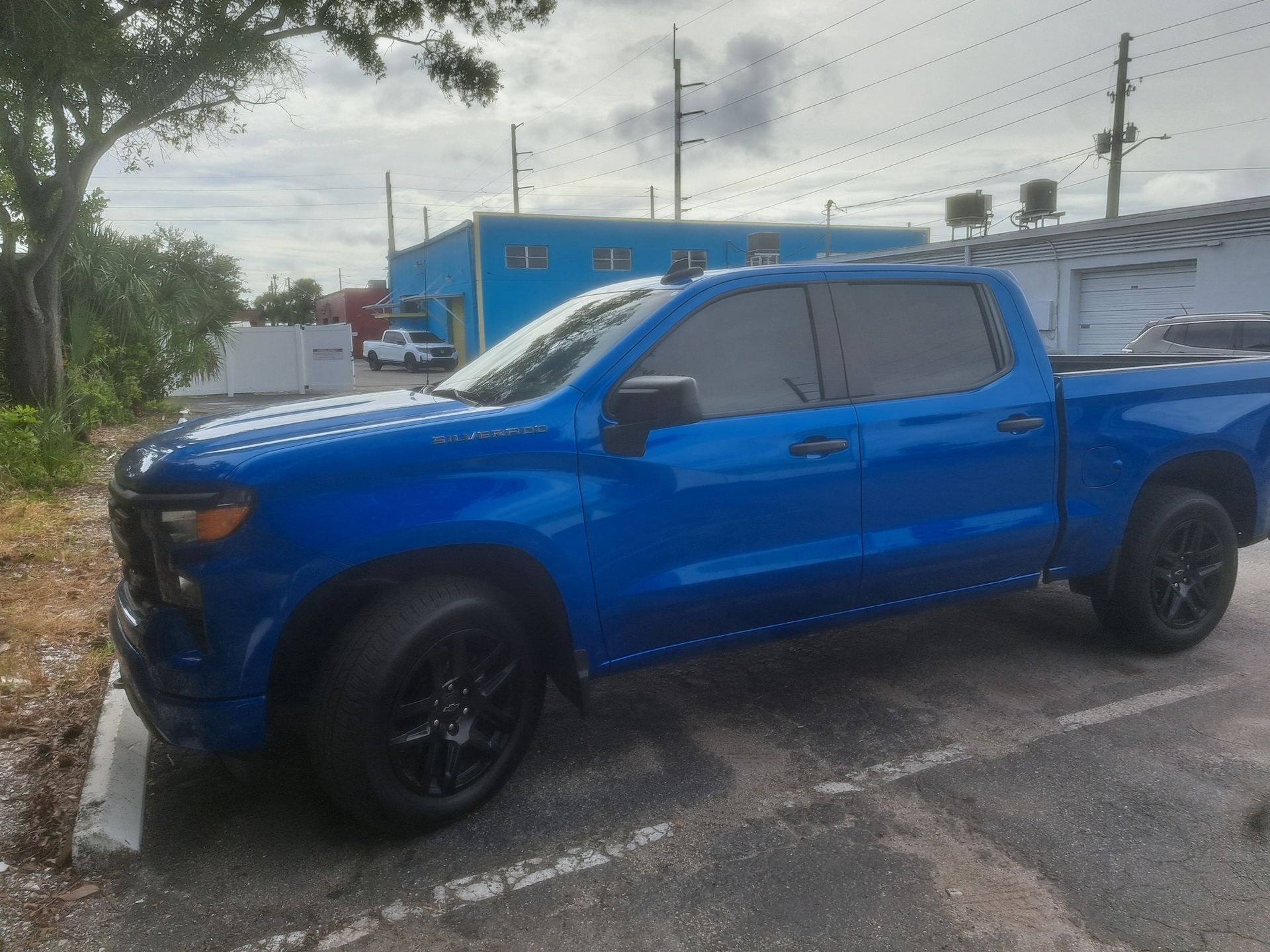 Blue pickup truck parked in a lot with dark tinted windows and black wheels.