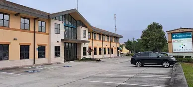 A two-story beige building with a large glass entrance and a sign for 