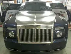 Blue Rolls Royce with silver hood and grill, doors open in a workshop.