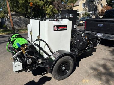 Portable industrial pump on trailer beside pickup truck on a sunny street
