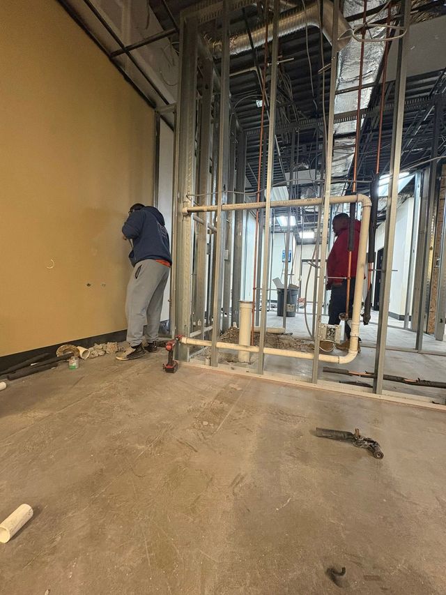 Construction site with exposed framing and two workers near a wall opening